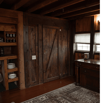 Rustic room with dark wooden paneling and a sliding barn door beside a storage console at La Tourelle Hotel and Spa