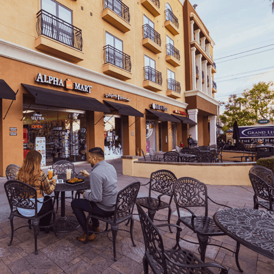 Couple dining at outdoor tables in front of shops at Grand Legacy at The Park Anaheim