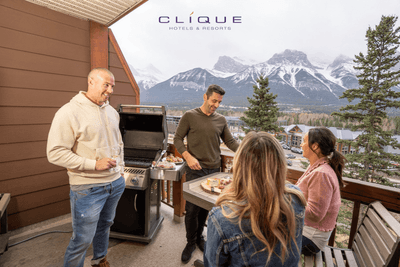 Group of four toasts with wine on a balcony, enjoying a cheese board and a stunning mountain view at Falcon Crest Lodge