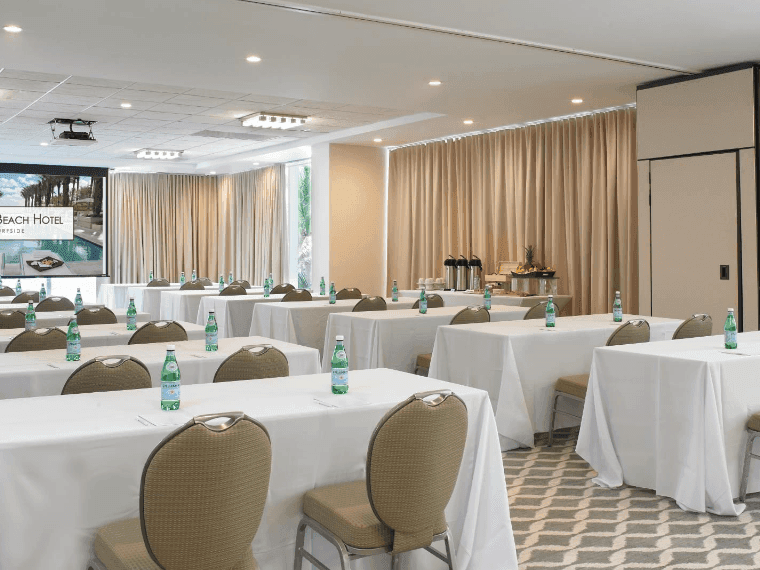 Salle de réunion aménagée en configuration « salle de classe », face à un écran de présentation, dans l'espace « Monet East » de l'hôtel Grand Beach à Surfside