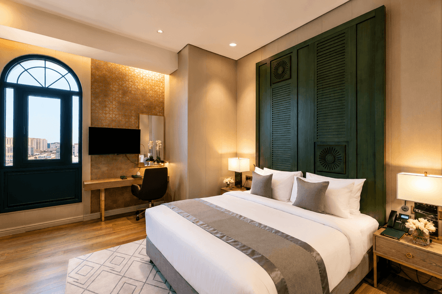 King bed beside arched window near desk with swivel office chair in Deluxe skyline view at Naviti by Warwick Jeddah