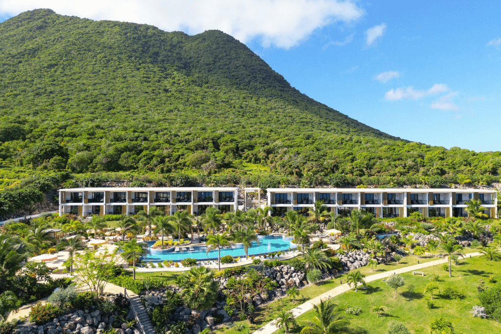 Aerial view of Golden Rock Resort, featuring an outdoor pool surrounded by lush greenery and majestic mountains