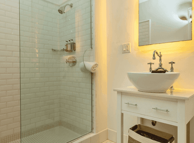 Bathroom interior with a white basin sink, a large mirror, and a walk-in shower in a cozy room at The Exeter Inn