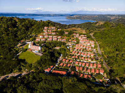 Aerial view of a group of houses on a hill surrounded by trees near Villas Sol Beach Resort