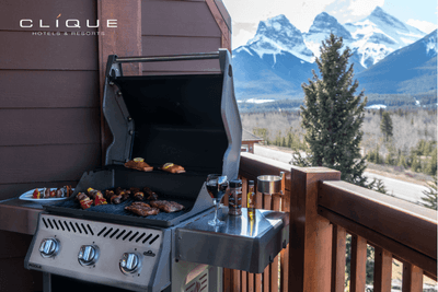 Barbecue grill with sizzling steaks and vegetables sits on a wooden balcony at Falcon Crest Lodge