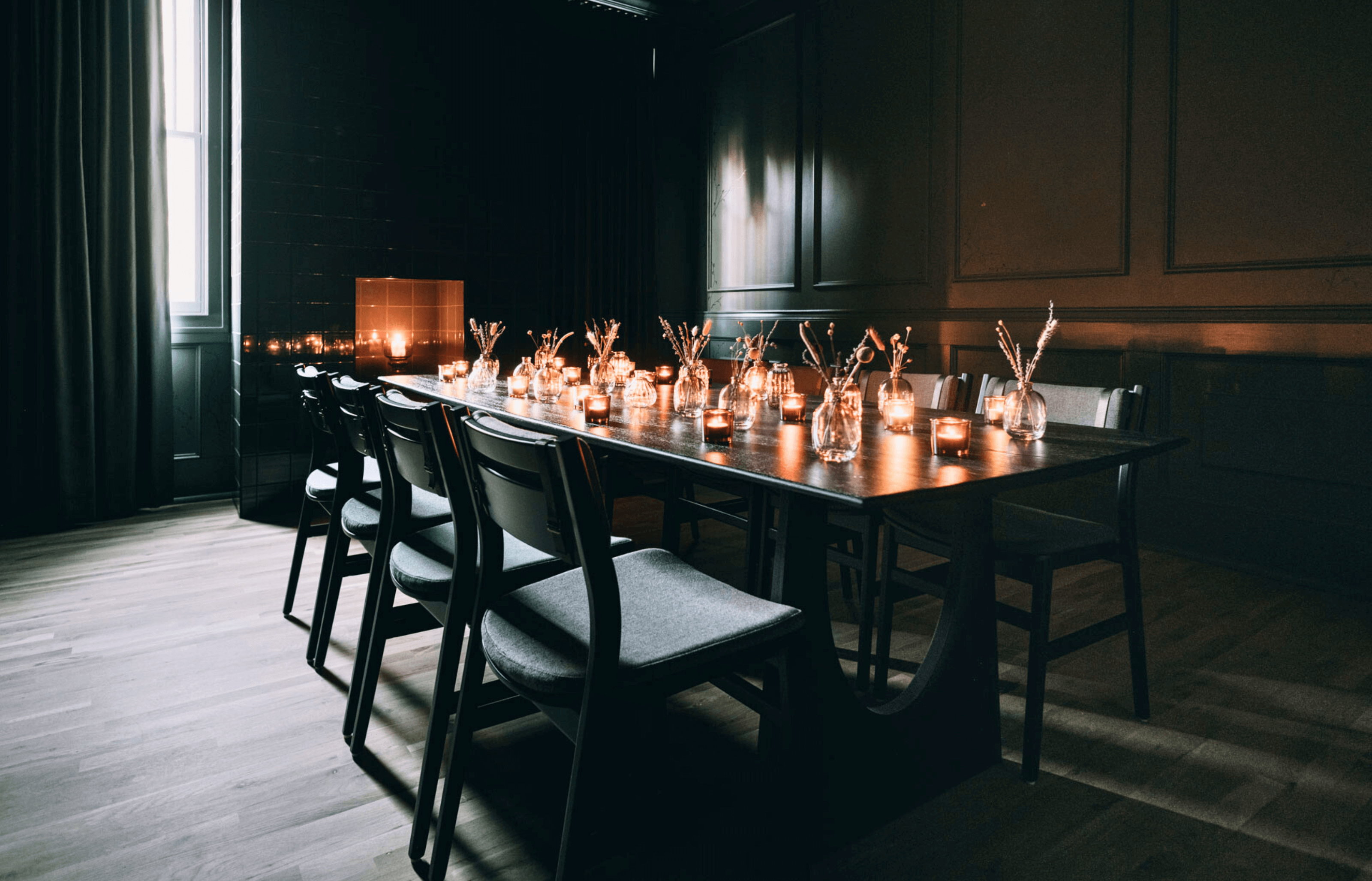A door opening to a private event room with a tiled fireplace, tv, and a table that seats ten guests.
