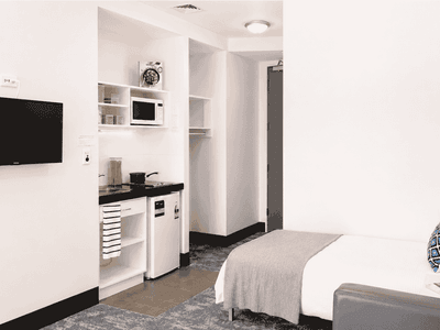 Modern studio apartment with kitchenette, wall-mounted TV, and comfortable bed at Student Living Waymouth