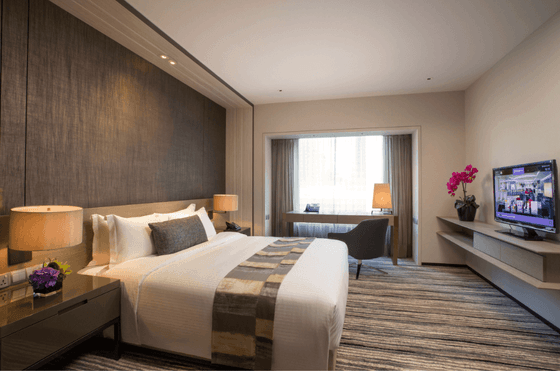 King-size bed, a TV, and a work desk in the Executive Suite at Carlton Hotel Singapore