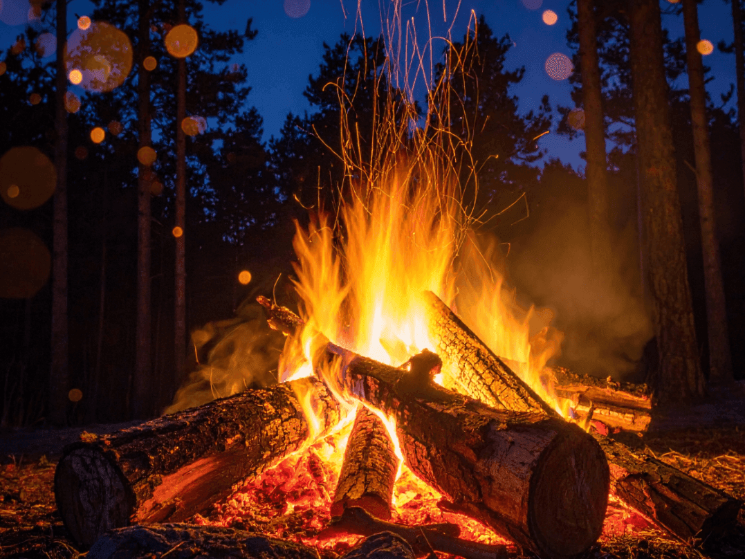 Foc de tabără în pădure în timpul nopții pentru Oferta 1 Mai în Poiana Brașov.
