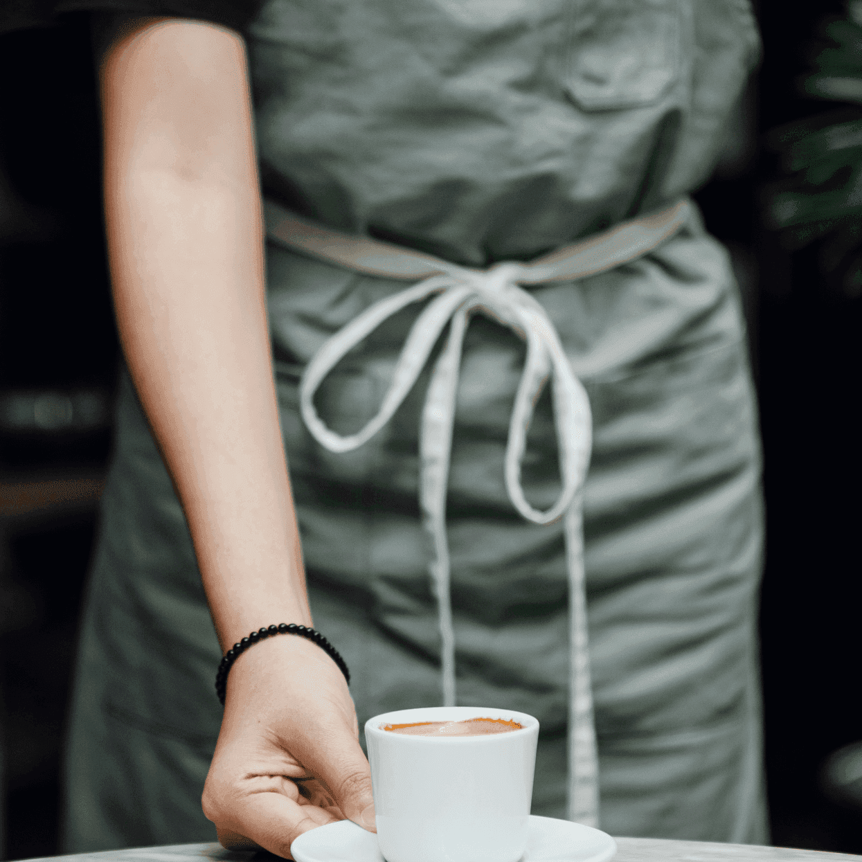 A Barista placing a fresh cup of coffee on a table