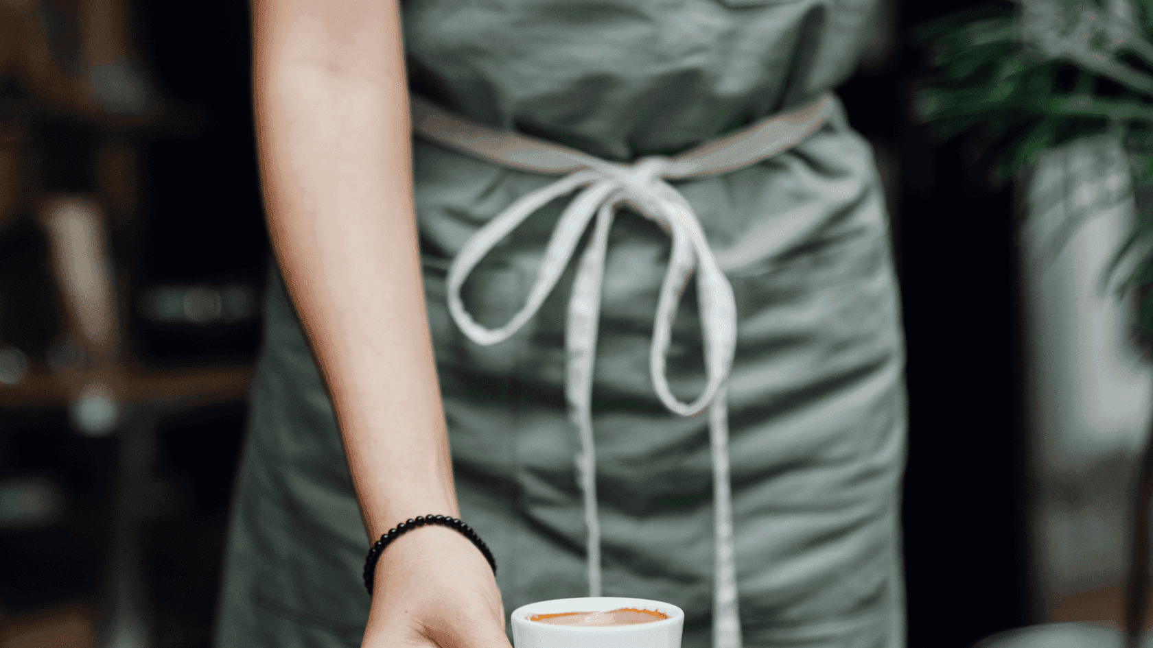 A Barista placing a fresh cup of coffee on a table