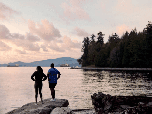 A couple stretches on a beach in Stanley Park, Vancouver