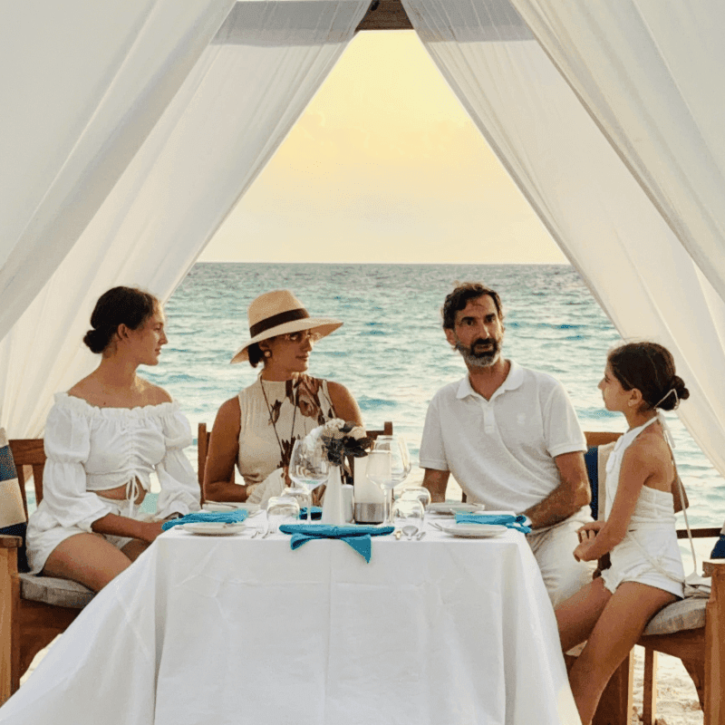 Family of four having a pergola dinner with ocean views during golden hour at Grand Park Kodhipparu