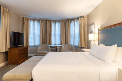 Guest room with bed, television, seating area, and large windows at Anchorage By The Sea