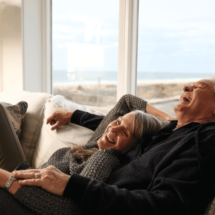 Couple with grey hair laughing and lounging in a suite at ICONA Cape May with a beach view hotel room in NJ
