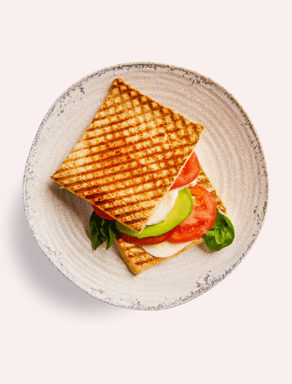 A delicious grilled sandwich with tomato, mozzarella, and avocado, a perfect light bite served at The Londoner Hotel