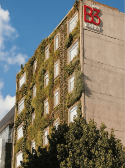 Vertical garden wall on hotel exterior with red rooftop signage under clear sky above green foliage at Hotel B3 Sibelius