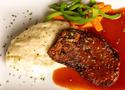 Gourmet grilled steak with rich gravy sauce served next to creamy mashed potatoes and green peppers at Rodd Royalty