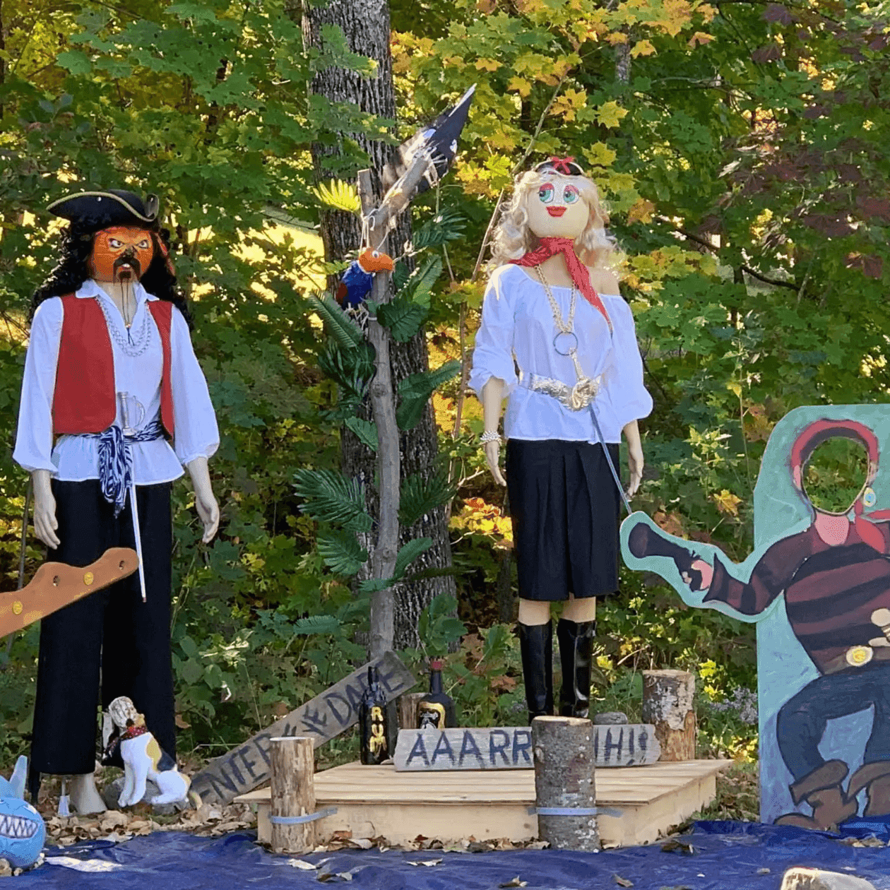 Outdoor pirate display with two mannequins and a photo cutout near colorful fall foliage at Grand Summit Hotel at Attitash