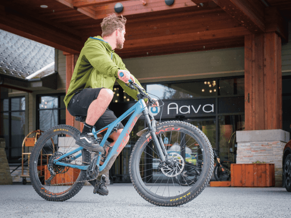 Man riding a bicycle by the hotel entrance, Aava Whistler Hotel
