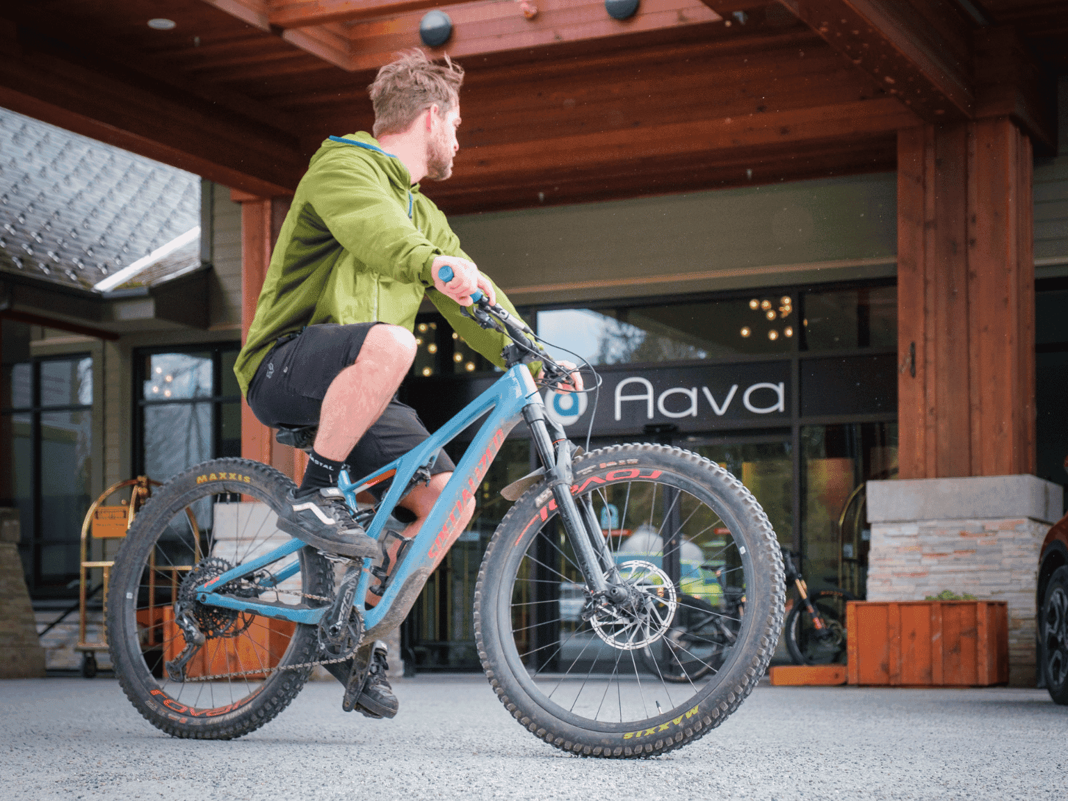 Man riding a bicycle by the hotel entrance, Aava Whistler Hotel