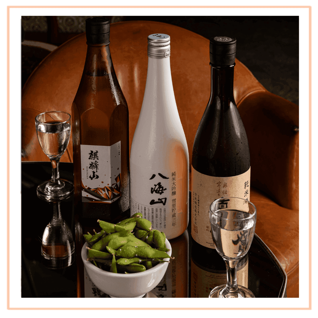 Premium sake bottles with glasses and a bowl of edamame in Blue Ribbon Sushi Bar & Grill at The Plymouth Hotel South Beach