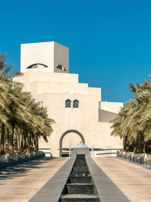 مدخل متحف الفن الإسلامي مع أشجار النخيل ونافورة على طول الممر.