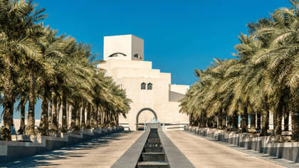 مدخل متحف الفن الإسلامي مع أشجار النخيل ونافورة على طول الممر.
