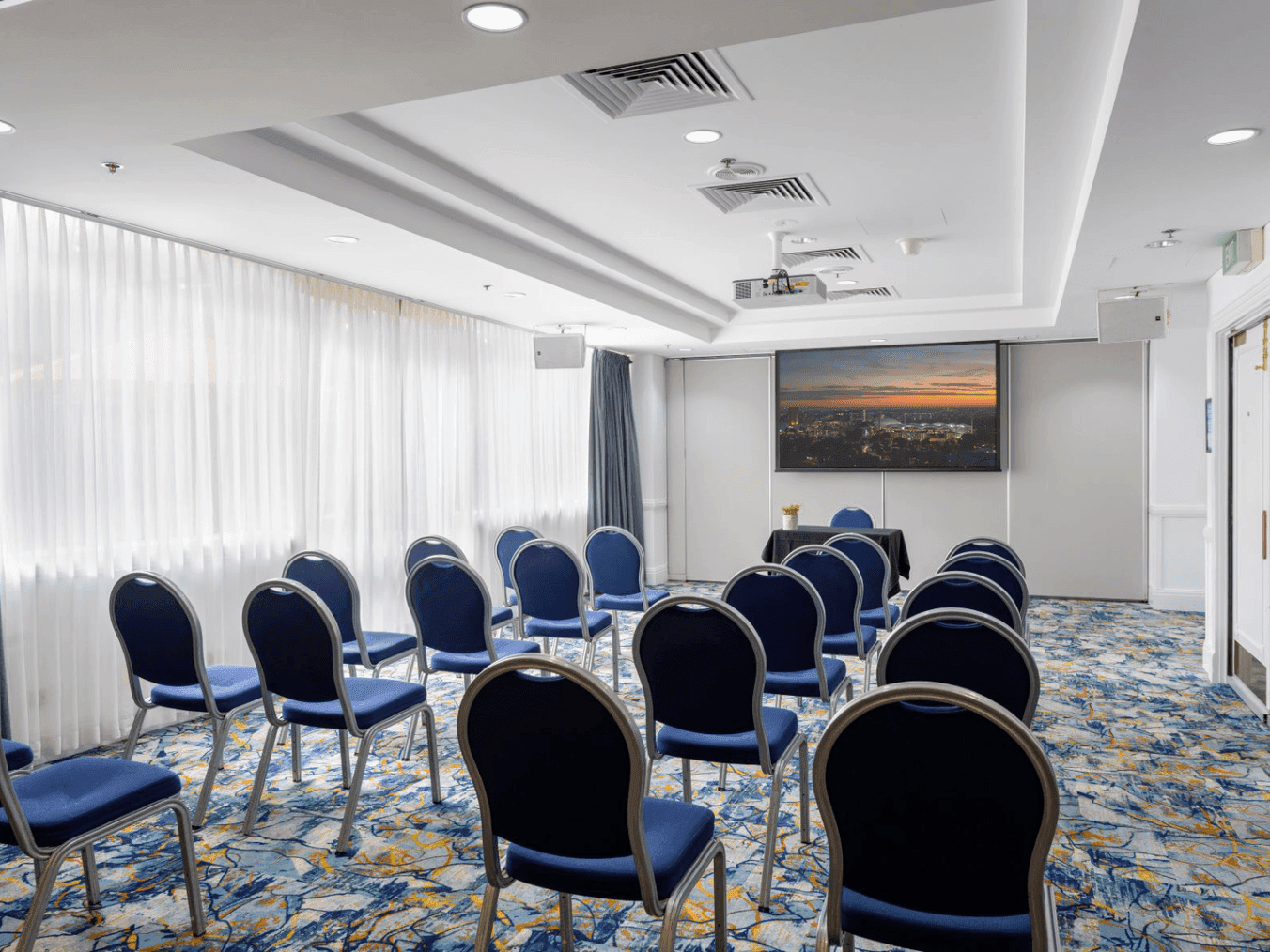 Chairs arranged in rows with a projector screen in the Torrens 1 or 2 event room at Hotel Grand Chancellor Adelaide.