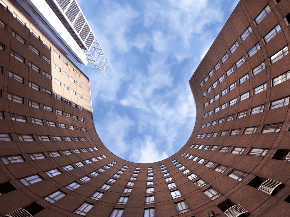 Modern brick apartment building courtyard photographed from below showing geometric architecture against blue sky