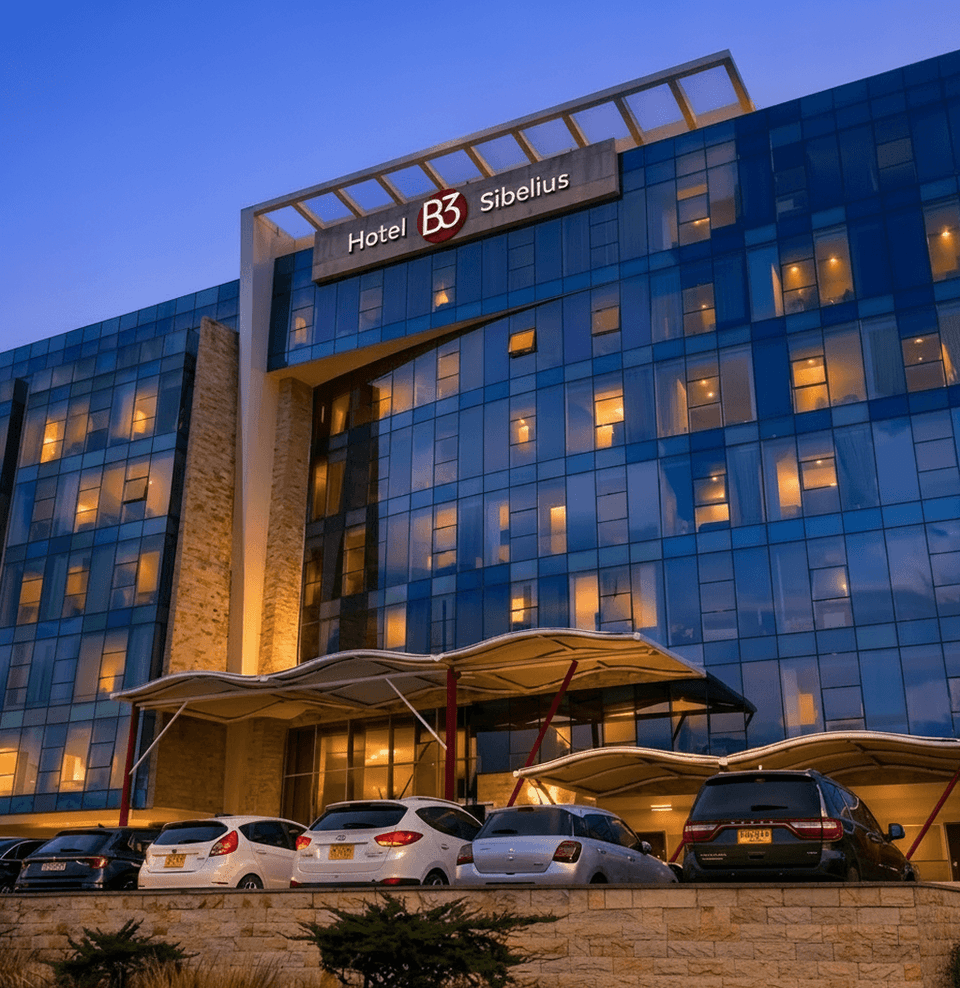 Exterior of Hotel B3 Sibelius with a blue glass facade and parked cars near Unika Hotels, an elite Bogota hotel