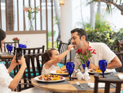 Daughter feeding for father at a dining table in Sunset Restaurant at at Buenaventura Grand Hotel and Spa