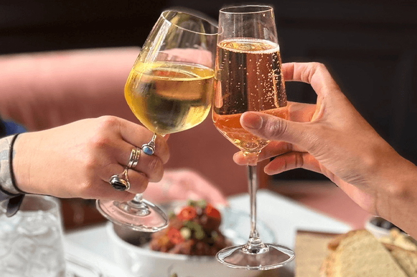 Couple toasting glasses of champagne and wine over a dining table in Gott\'s Bar & Kitchen at The Met Hotel Leeds, England