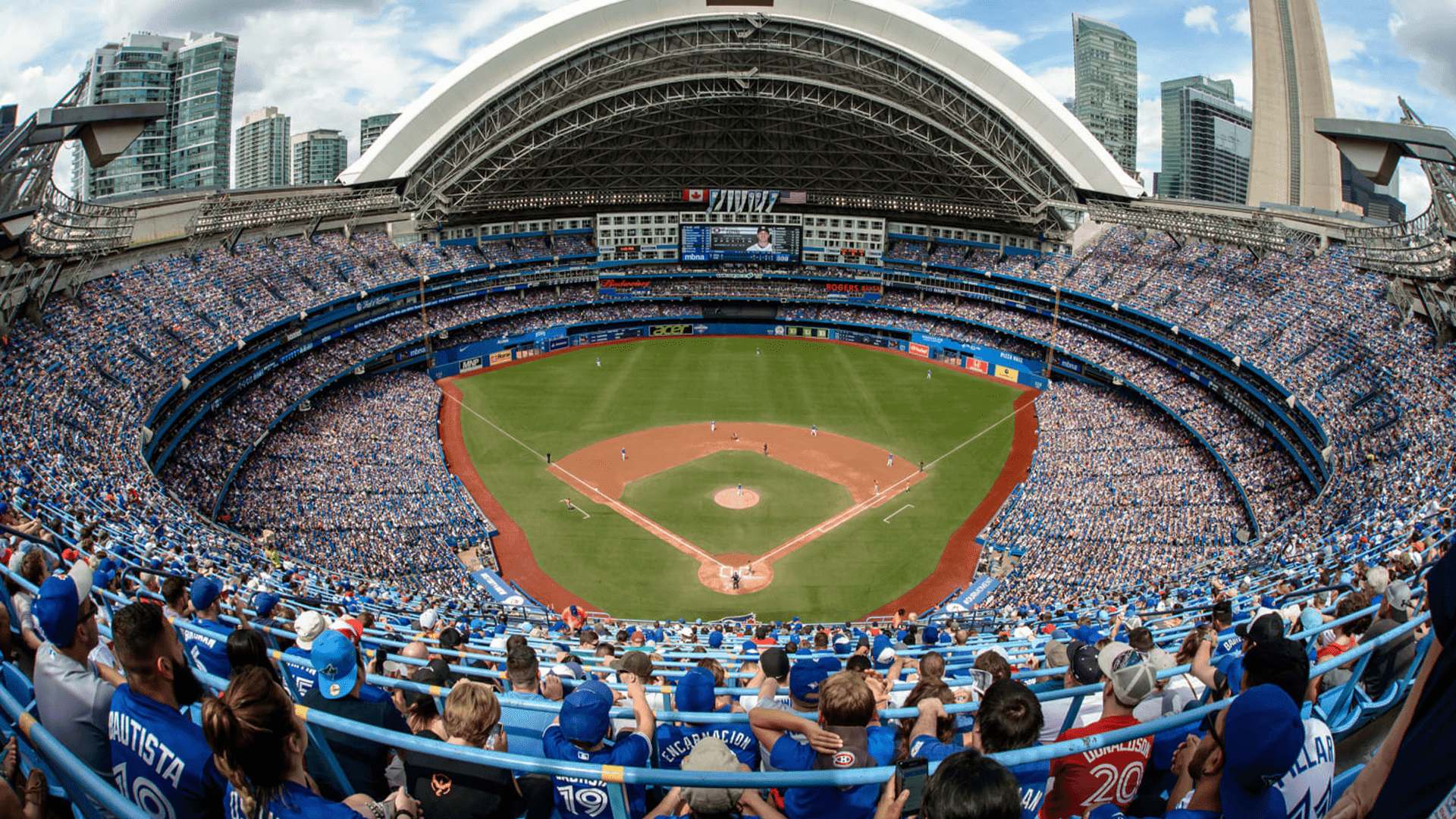 Rogers Centre with fans fill blue stadium seats surrounding a baseball diamond under a retractable roof near Hotel X Toronto