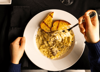 Creamy fettuccine pasta with grilled garlic bread served on a white plate in Wally\'s Restaurant & Lounge at Rodd Royalty