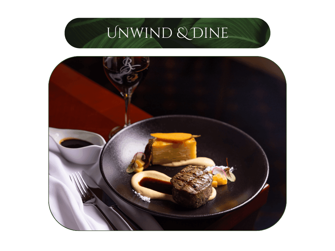 Plate with steak, sauce, and side dish next to wine glass illustrating breakfast plus $100 dining credit offer.