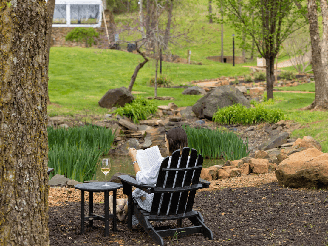 Person reading a book while enjoying glass of wine in the garden at the Inn at Willow Grove