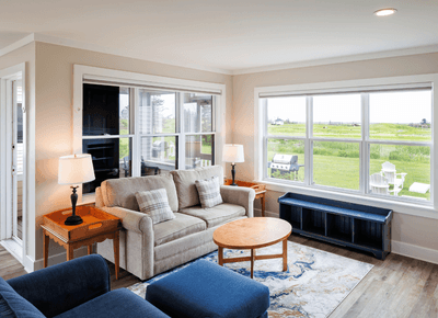 Two-Bedroom Cottage View with sofa, blue seating, & large windows overlooking greenery at Rodd Crowbush Golf & Beach Resort