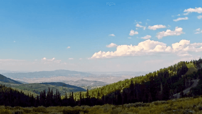 Panoramic view of green hills, lush forests and distant mountains under a clear sky near Hotel Park City Autograph Collection
