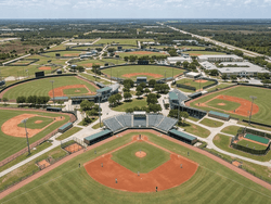 Aerial view of baseball diamonds surrounding a central stadium with grandstands and trees near Star Suites Vero Beach