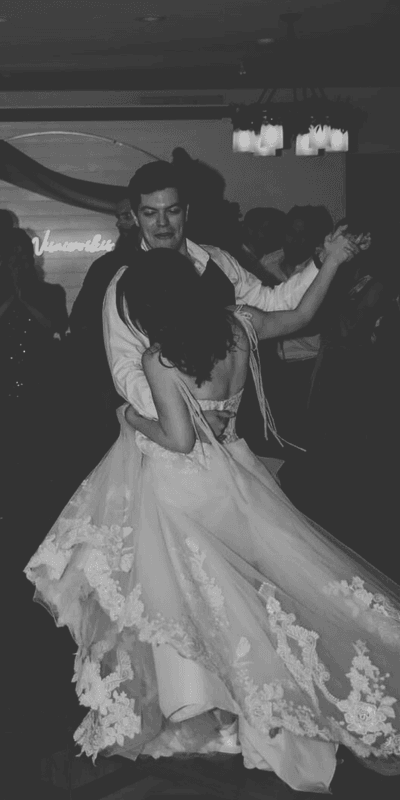 Groom and bride in white lace dresses dancing at an indoor reception during a wedding event at La Tourelle Hotel and Spa