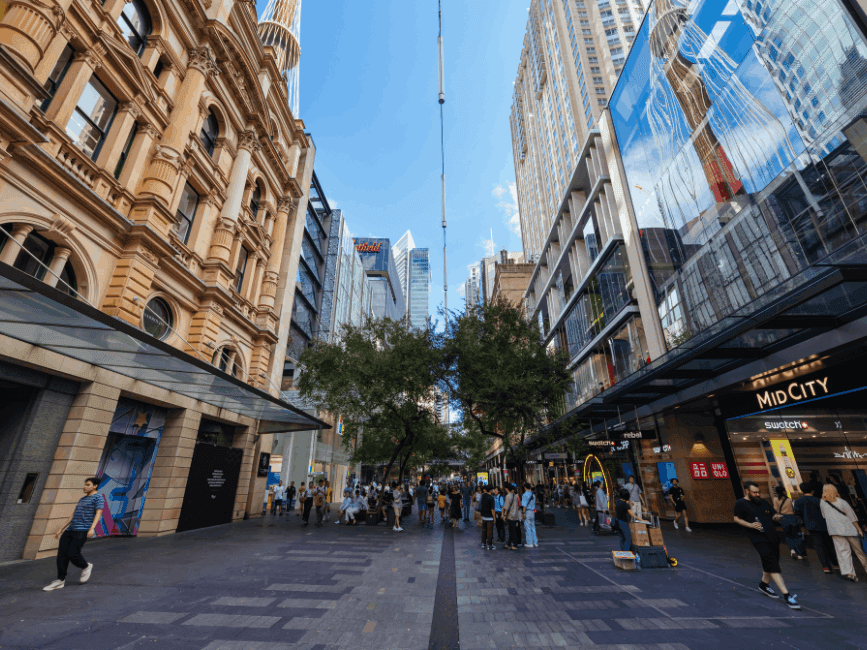 Busy Pitt Street Mall with shoppers and buildings under a clear sky.