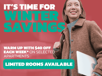 Smiling student in brown coat holding coffee cup with winter savings promotion for Student Living - City West
