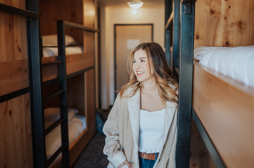 A Lady beside a bed in the Shared bunkroom at Kinship Landing