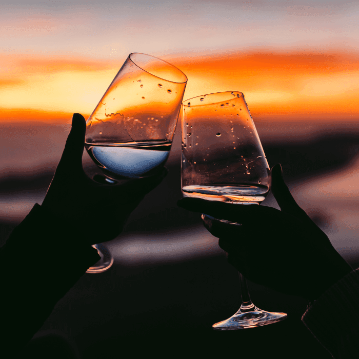 Wine glasses cheers in front of ocean at dusk Wine Dine & Unwind Couples Getaway in NJ