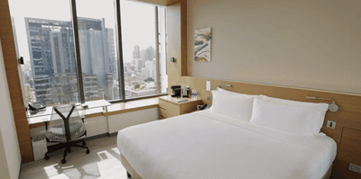 Work desk and nightstand by the bed in The Mint Den Bedroom with a city view at One Farrer Hotel