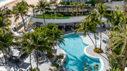 Tropical lagoon pool deck with resort loungers and palm-lined pathways.