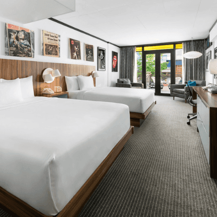 Retro-styled motel room with two beds, vintage music posters, wood paneling, and mid-century modern furnishings in Massachusetts