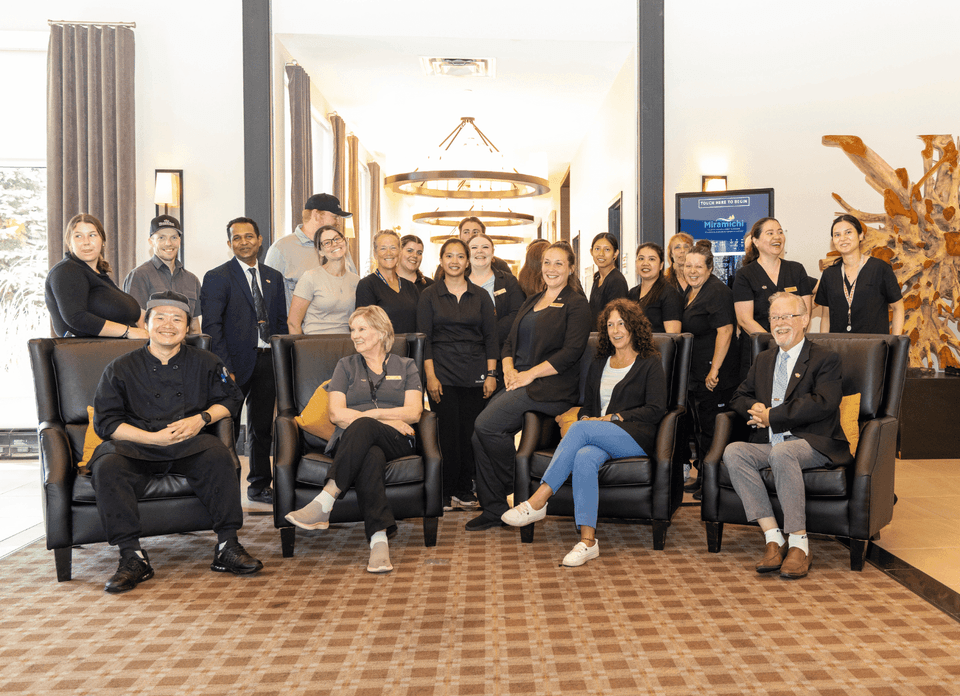 Smiling hotel staff team posing together in the bright, modern lobby lounge area at Rodd Hotels & Resorts