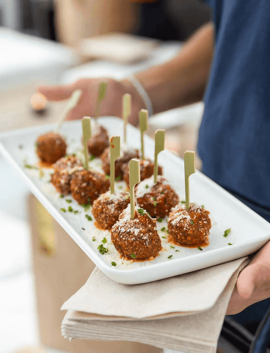 A serving tray of meatballs with parmesan cheese and parsley.
